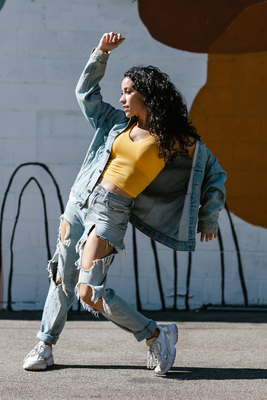a woman in denim jacket and pants dancing on the street